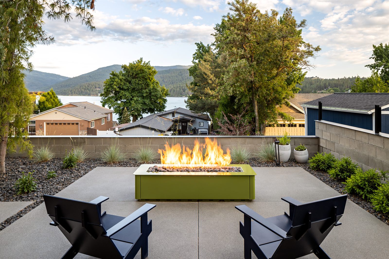 Concrete patio with a modern fire table and lake views at dusk